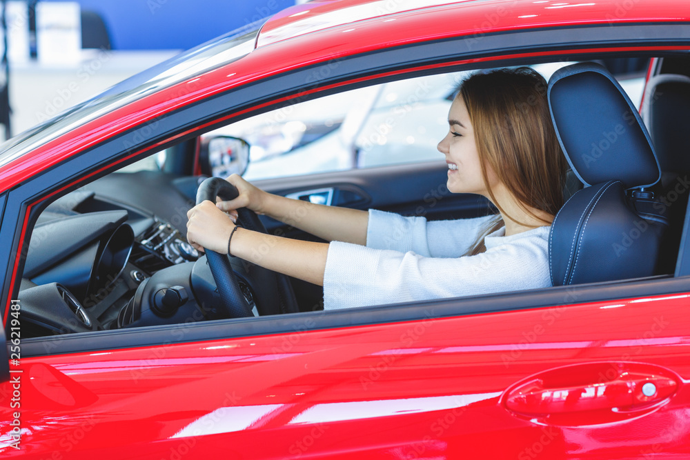 Beautiful happy woman choosing a car at the dealership