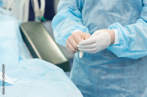 Surgeon preparing for operation putting on latex gloves