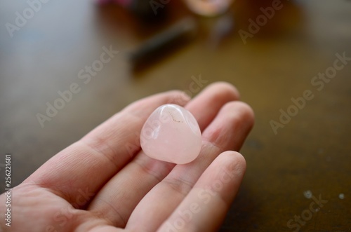 Holding Rose Quartz, natural lighting. Pink, romantic healing crystal. Pastel rose quartz chunks. Person holding small pink gemstone. Light pink, rough and tumbled crystals. 