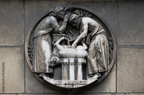 Aruspices, a priest in ancient Rome who practiced divination by the inspection of the entrails of animals. Stone relief at the building of the Faculte de Medicine Paris, France  photo