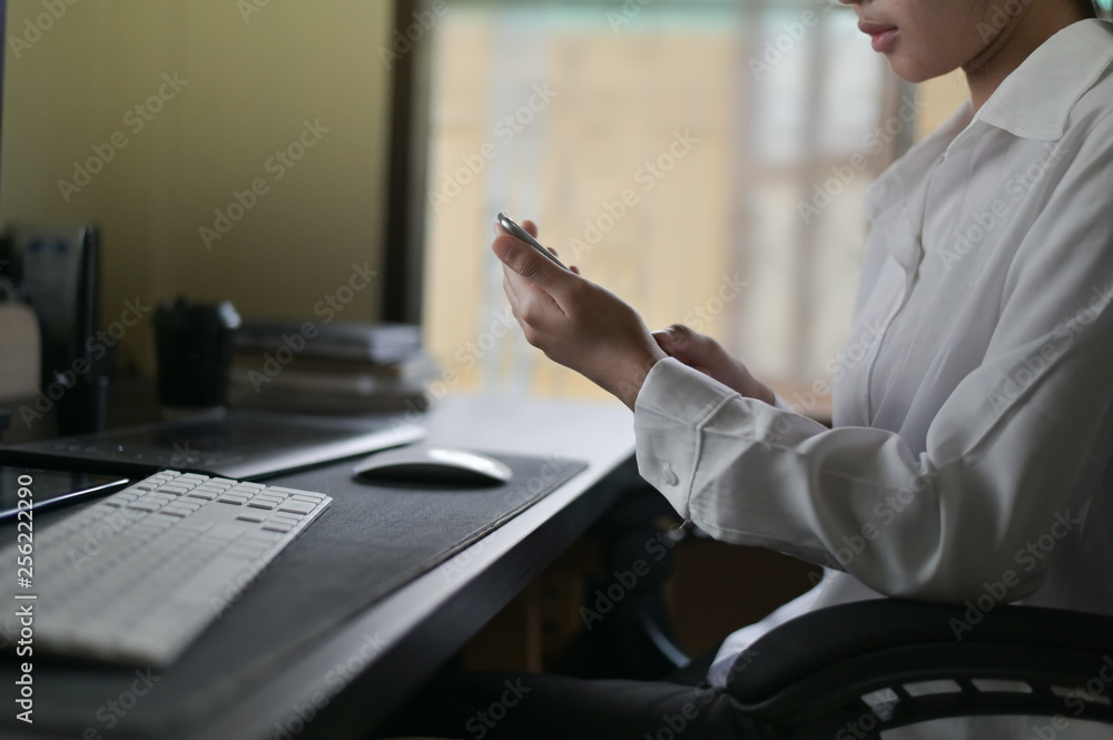 Cropped shot woman using mobile phone on office desk. Cropped shot woman using mobile phone on office desk.