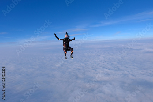 Skydiving. Pretty girl is sitting above white clouds.