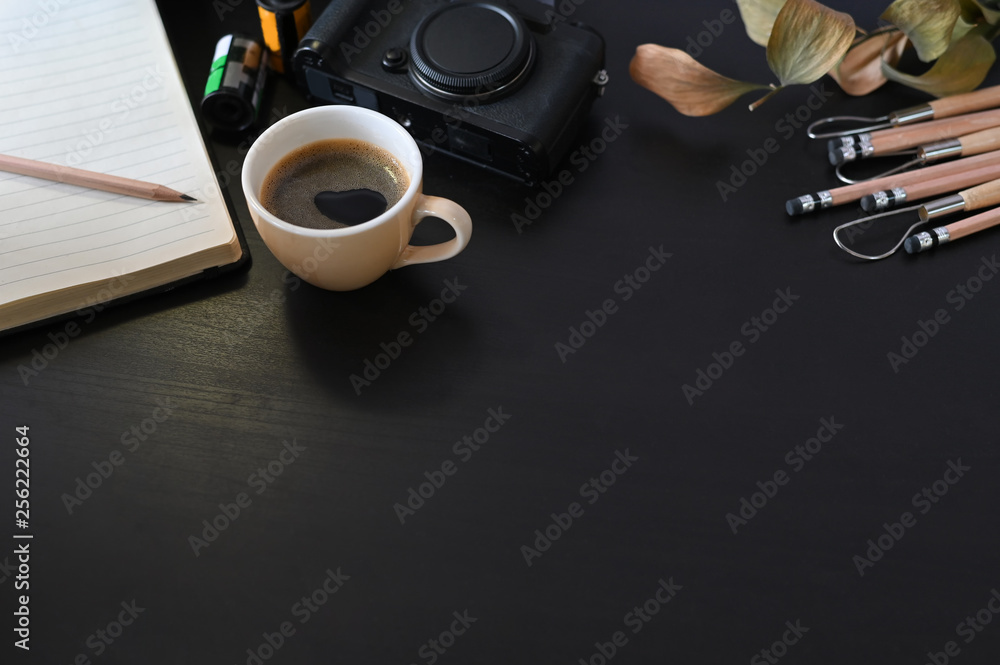 Fototapeta premium Creative workplace camera, coffee and note paper on black table with selective focus.