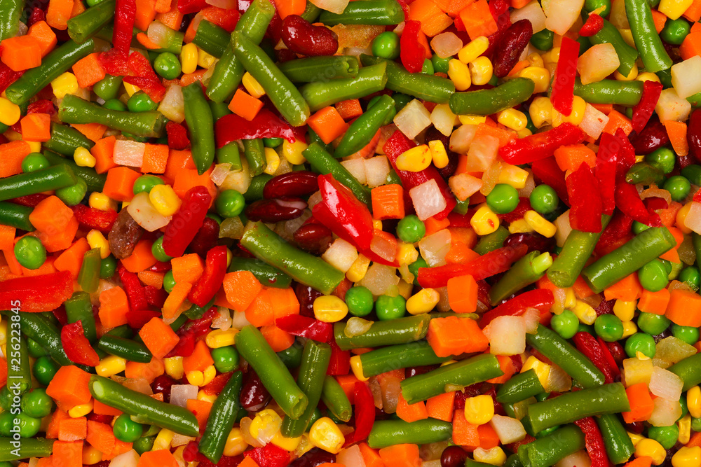 Sliced vegetables, corn, beans, peas, carrots, sweet peppers background.