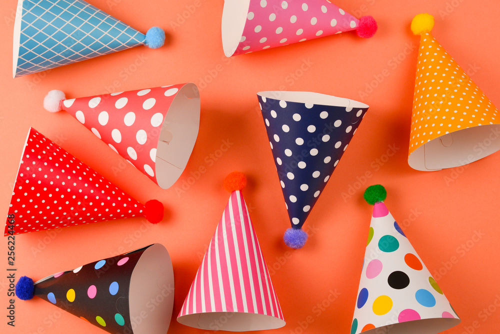 Obraz premium Colorful birthday caps on orange background. Top view.