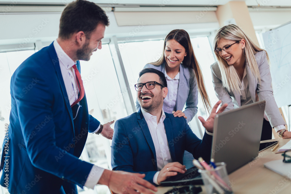 Group of young business people working and using laptop while sitting at the office desk together. Selective focus. Group of young business people working and using laptop while sitting at the office desk together. Selective focus.