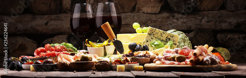 Italian antipasti wine snacks set. Cheese variety, Mediterranean olives, crudo, Prosciutto di Parma, salami and wine in glasses over grunge background. photo