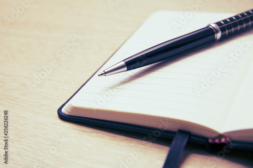 Wallpaper Mural Black pen lies on the opened note cover on the spring on a light wooden table. Place to write. Torontodigital.ca