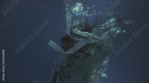 Girl in a white dress with ribbons under the water