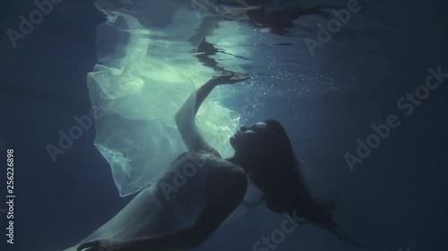 Girl in a white dress with ribbons under the water