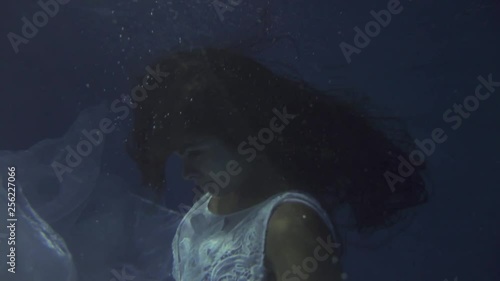 Girl in a white dress with ribbons under the water