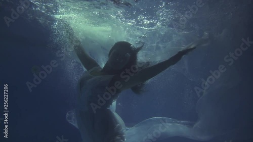 Girl in a white dress with ribbons under the water