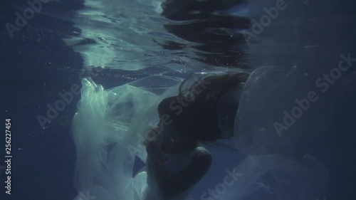 Girl in a white dress with ribbons under the water
