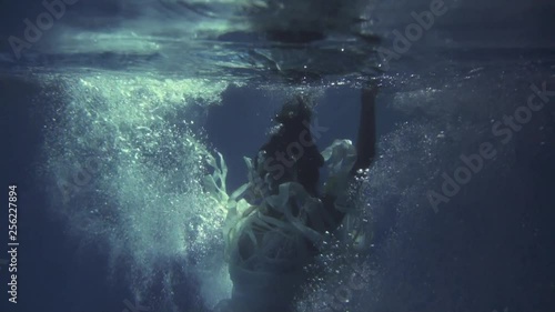 Girl in a white dress with ribbons under the water