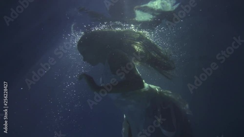 Girl in a white dress with ribbons under the water