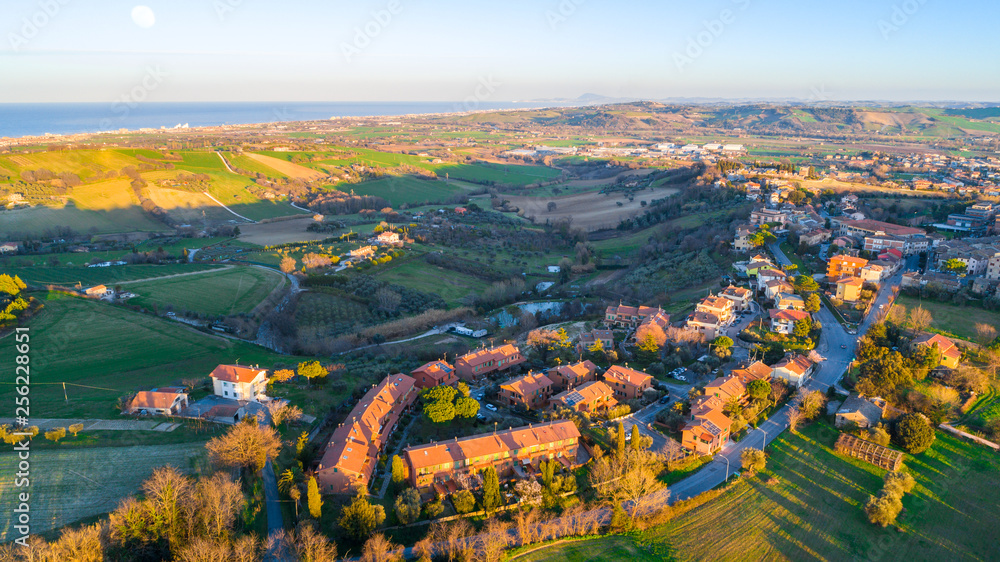 aerial view of a residential area in a rural town in italy. buildings and countryside hills landscape at sunset