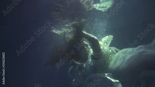 Girl in a white dress with ribbons under the water