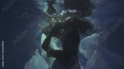 Girl in a white dress with ribbons under the water