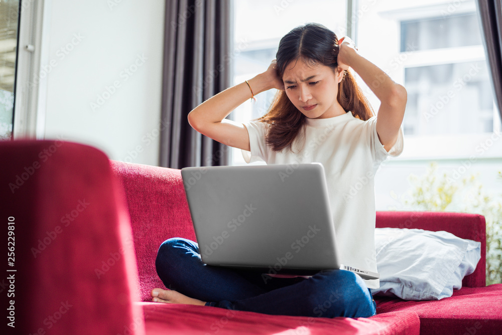 Asian young exhausted businesswoman having headache while using laptop on sofa in her house. Business people worry and stress about job deadline concept. Online shopping marketing technical problem Asian young exhausted businesswoman having headache while using laptop on sofa in her house. Business people worry and stress about job deadline concept. Online shopping marketing technical problem