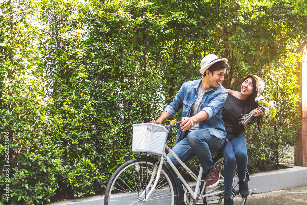 Happy couple riding bicycle together in romantic view park background. Valentine's day and wedding honeymoon concept. People and lifestyles concept. Happy couple riding bicycle together in romantic view park background. Valentine's day and wedding honeymoon concept. People and lifestyles concept.