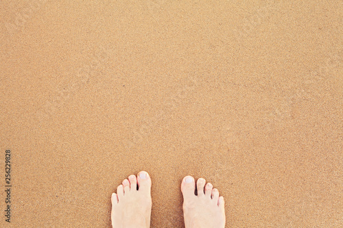 Top view of feet on sea sand. Vacation on ocean beach and summer holiday concept