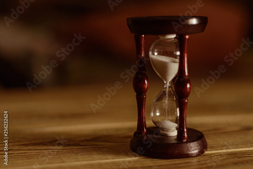 The concept of time. Hourglass on wooden background.