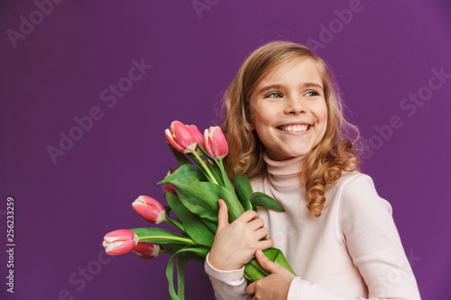 Portrait of a smiling little girl holding bouquet of tulips