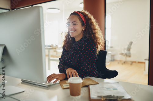 Smiling young businesswoman at work at her office desk