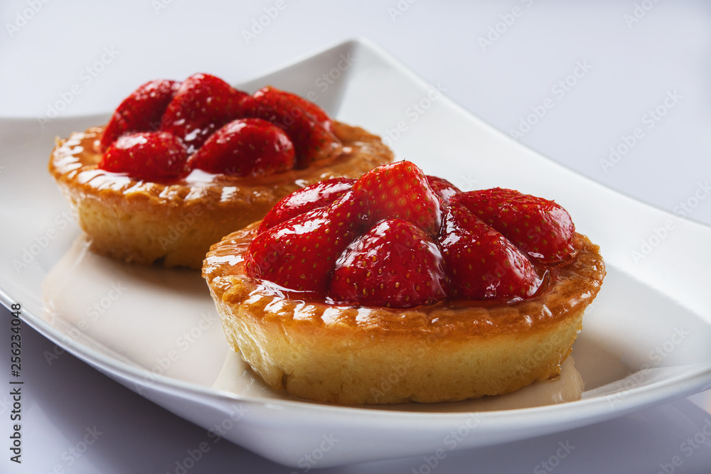 Basket-cakes with mascarpone cheese and decorated with strawberry on white plate. High Key. Close up. Selective focus. Basket-cakes with mascarpone cheese and decorated with strawberry on white plate. High Key. Close up. Selective focus.