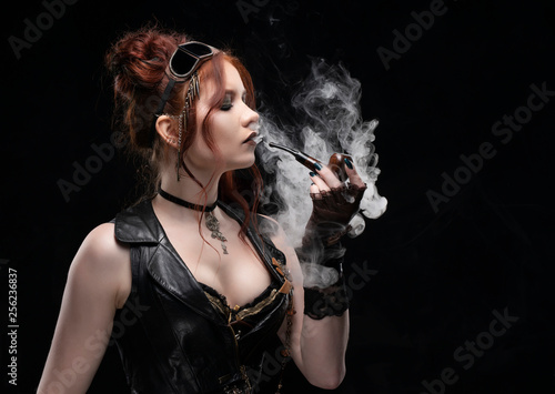 A beautiful red-haired cosplayer girl wearing a Victorian-style steampunk costume with a large breast in a deep neckline smoking a pipe in a puff of smoke a black background