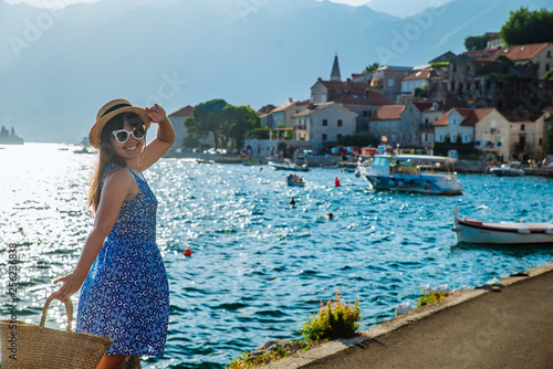 young pretty stylish woman walking by city quay. sea and mountains on background photo