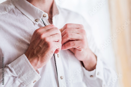 Man buttoning the top button on the shirt