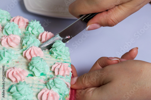 A woman is cutting a cake. Waffle cake made from cream soaked cakes. Decorated with cream flowers.