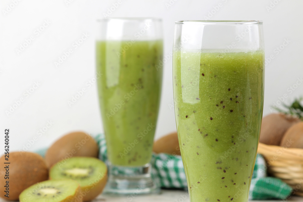 Kiwi smoothies in a glass next to fresh kiwi slices on a light marble table. fruit drink. Kiwi smoothies in a glass next to fresh kiwi slices on a light marble table. fruit drink.
