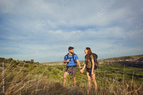 Happy couple of tourists with backpacks in nature