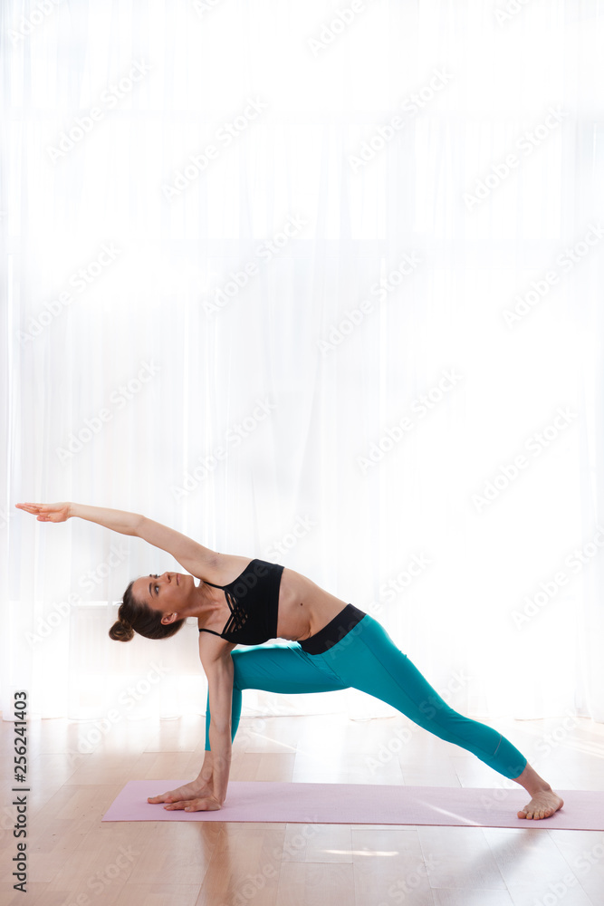Obraz premium Portrait of gorgeous young woman practicing yoga indoor