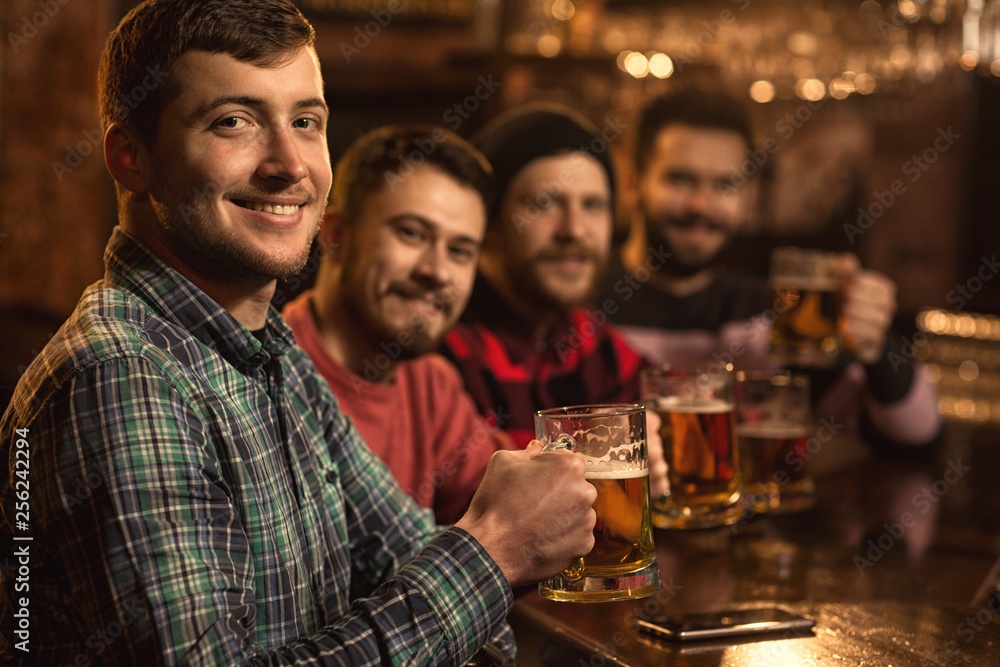 Happy male friends enjoying beer together at the bar