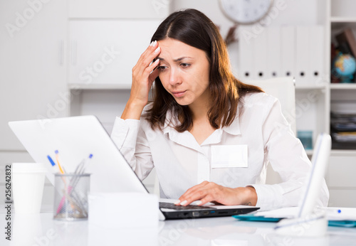 Upset  woman working with laptop and papers at the office © JackF