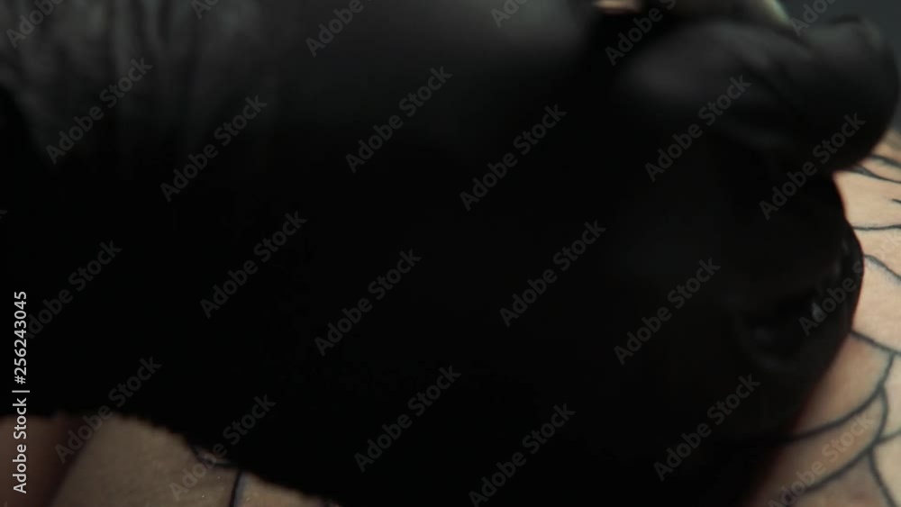 closeup tattoo master in protective black gloves draws sketch of future shadows on big flower tattoo with brown marker closeup tattoo master in protective black gloves draws sketch of future shadows on big flower tattoo with brown marker