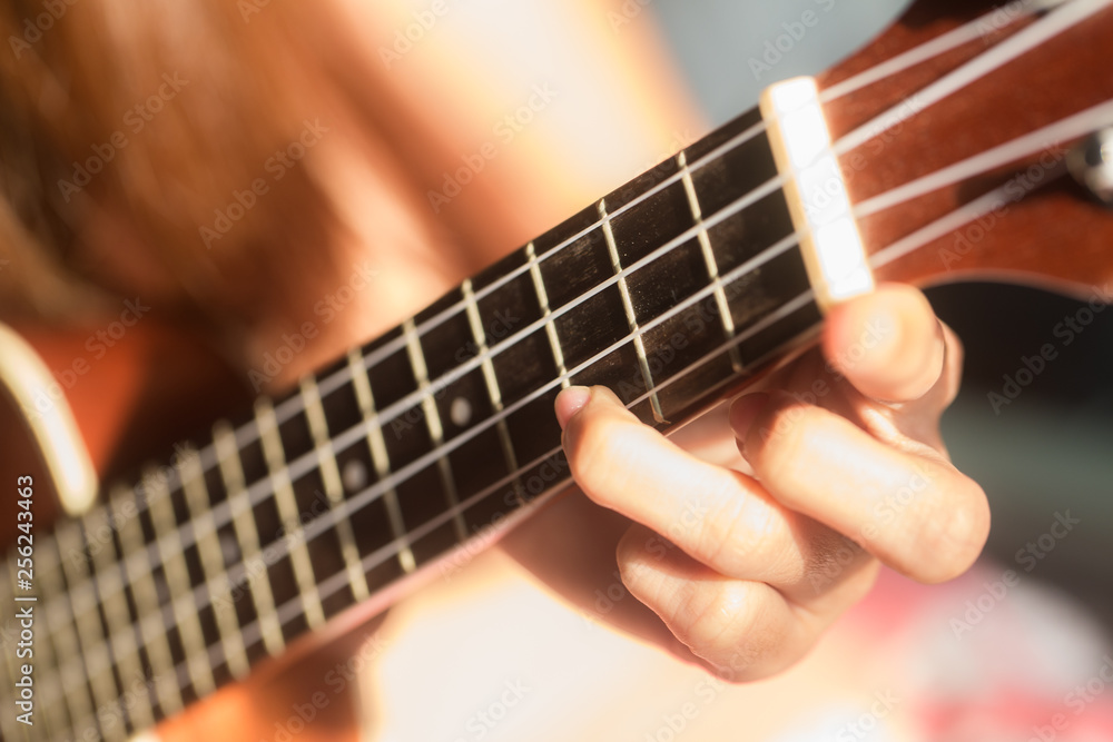 Fototapeta premium Women playing ukulele music with light of sun