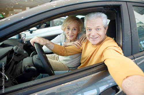 Happy loving senior couple choosing a new car to buy