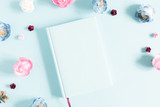 Flowers composition creative. Notebook, pink and light blue flowers on pastel blue background. Flat lay, top view, copy space