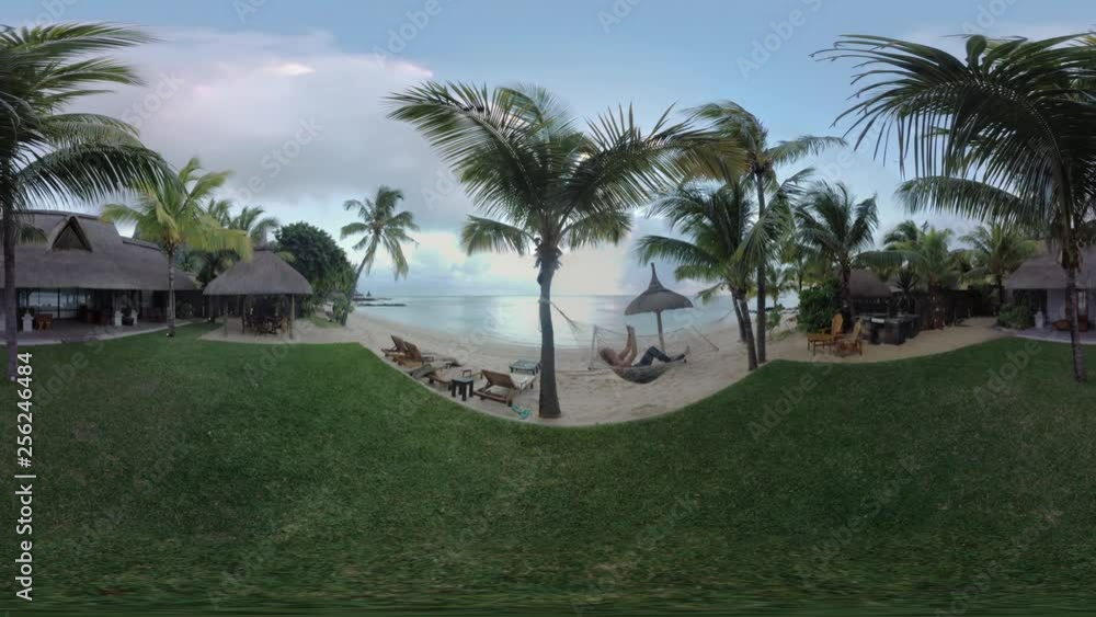 360 VR video. Scene with guest house on the ocean coast in tropics and woman relaxing in hammock with cellphone, Mauritius. Vacation at the seaside 360 VR video. Scene with guest house on the ocean coast in tropics and woman relaxing in hammock with cellphone, Mauritius. Vacation at the seaside
