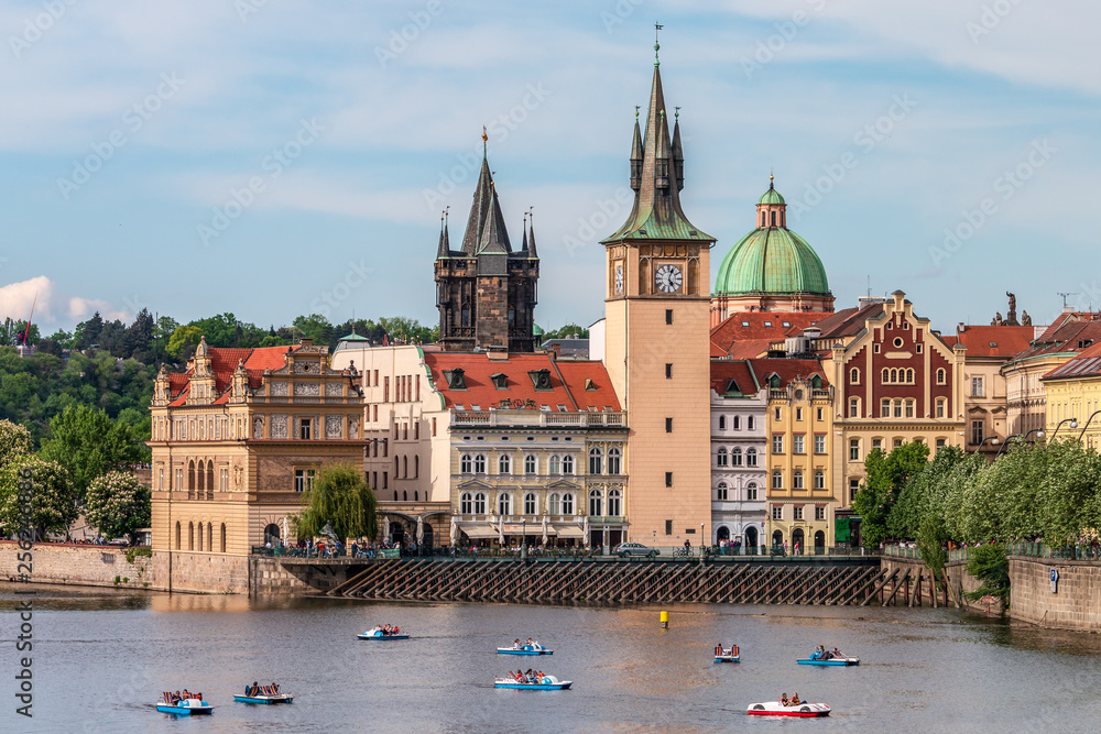 Summer Prague cityscape with touristic catamarans on Vltava river. View of Bedrich Smetana Museum, gothic Old Town Water Tower, green dome of baroque Church of St. Francis of Assisi and Bridge Tower.