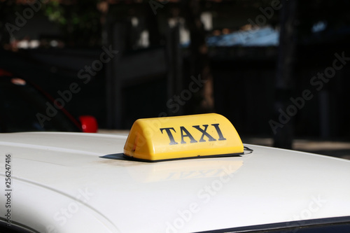 Taxi light sign or cab sign in yellow color with black text on the car roof at the street blurred background