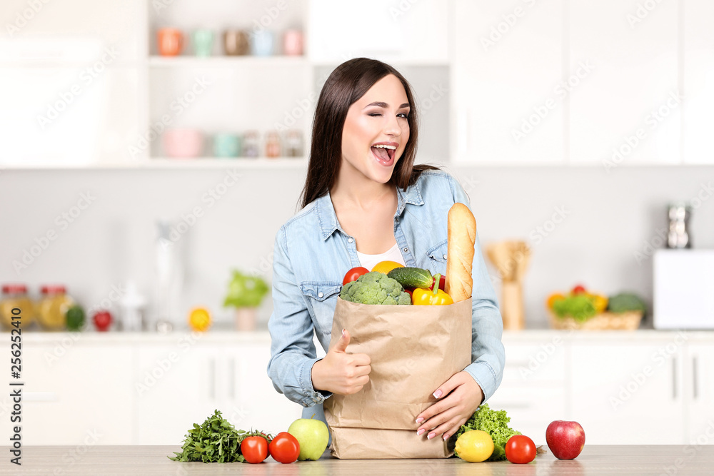 Beautiful woman standing on the kitchen with grocery shopping bag Beautiful woman standing on the kitchen with grocery shopping bag