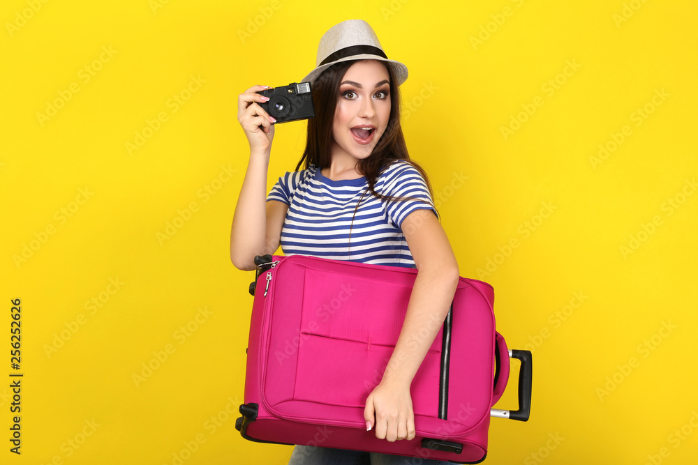 Young girl with suitcase on yellow background Young girl with suitcase on yellow background