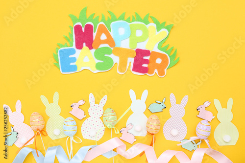 Fototapeta Naklejka Na Ścianę i Meble -  Colorful rabbits with eggs and text Happy Easter on yellow background