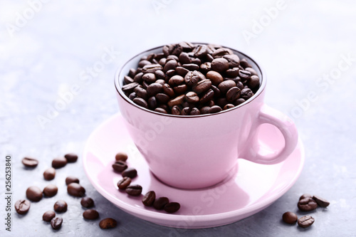 Coffee beans in pink cup on grey wooden table