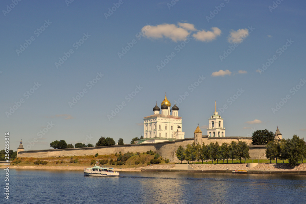 View of the Trinity Cathedral in the Pskov Kremlin from the Great River, on which the ship sails on a summer evening, Russia.